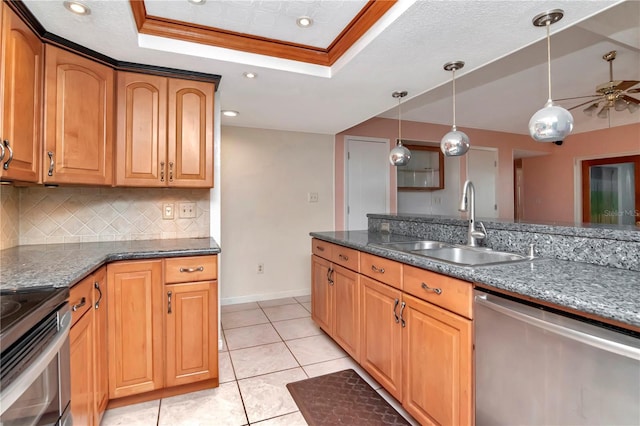 kitchen with sink, hanging light fixtures, stainless steel appliances, a raised ceiling, and dark stone counters