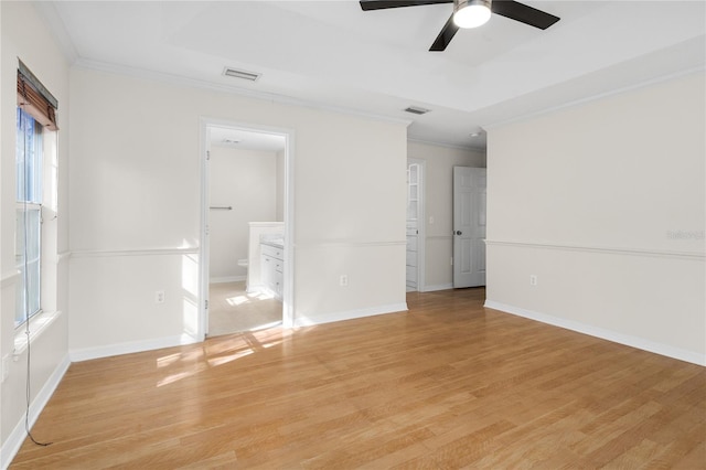 spare room featuring crown molding, a raised ceiling, and light wood-type flooring