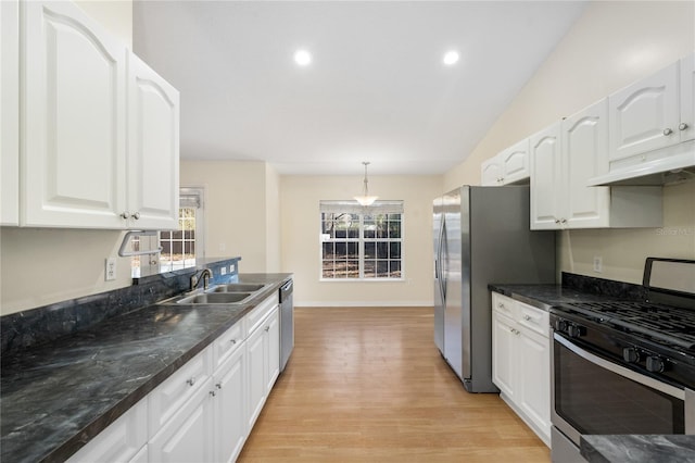 kitchen with sink, appliances with stainless steel finishes, white cabinetry, hanging light fixtures, and light hardwood / wood-style floors