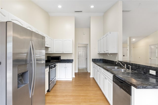 kitchen with sink, white cabinetry, kitchen peninsula, a towering ceiling, and stainless steel appliances