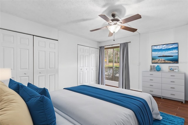 bedroom featuring ceiling fan, multiple closets, and a textured ceiling