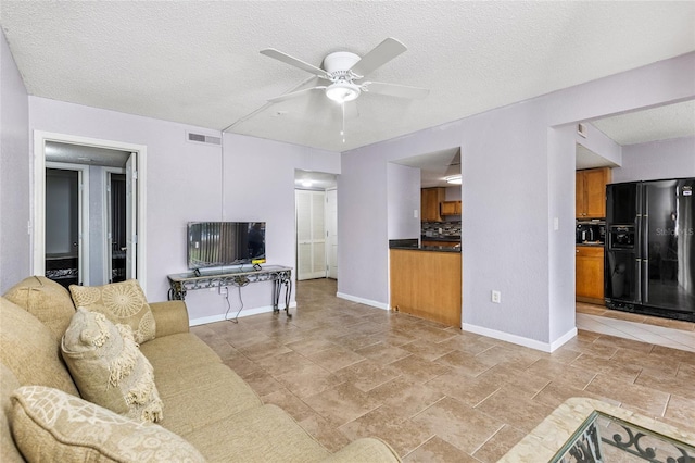 living room with ceiling fan and a textured ceiling