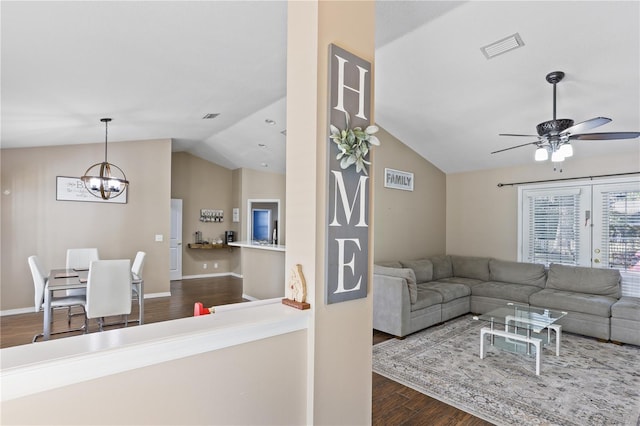 living room featuring ceiling fan with notable chandelier, dark wood-type flooring, and vaulted ceiling