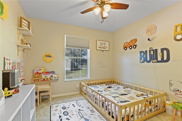 carpeted bedroom with ceiling fan and a nursery area