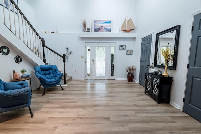 entryway with a towering ceiling and light hardwood / wood-style flooring