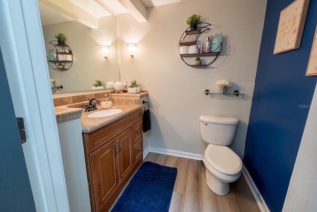 bathroom with hardwood / wood-style floors, vanity, beamed ceiling, tasteful backsplash, and toilet