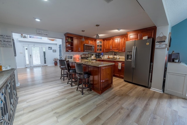 kitchen featuring light hardwood / wood-style floors, a kitchen breakfast bar, pendant lighting, and stainless steel appliances