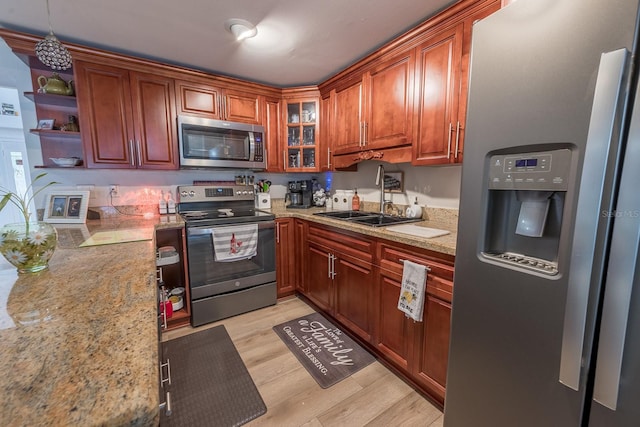 kitchen featuring light hardwood / wood-style floors, sink, light stone counters, and appliances with stainless steel finishes