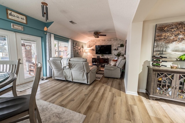 living room featuring ceiling fan, light hardwood / wood-style floors, a textured ceiling, and lofted ceiling