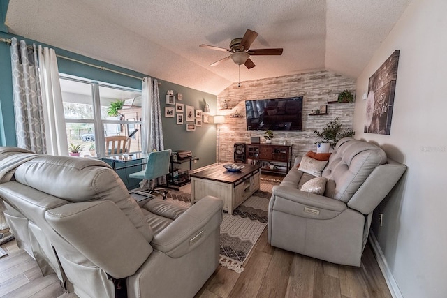 living room with lofted ceiling, ceiling fan, a textured ceiling, and light hardwood / wood-style floors