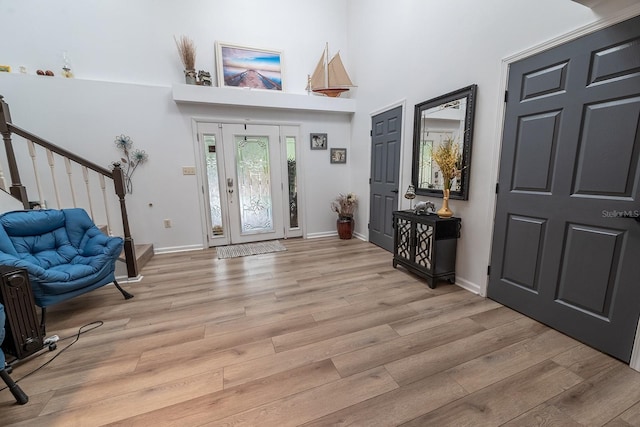 entrance foyer with light hardwood / wood-style floors and a towering ceiling