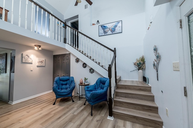 stairway with hardwood / wood-style flooring, a towering ceiling, and ceiling fan