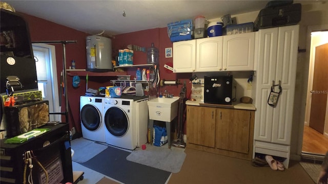 washroom with cabinets, electric water heater, sink, and washer and clothes dryer