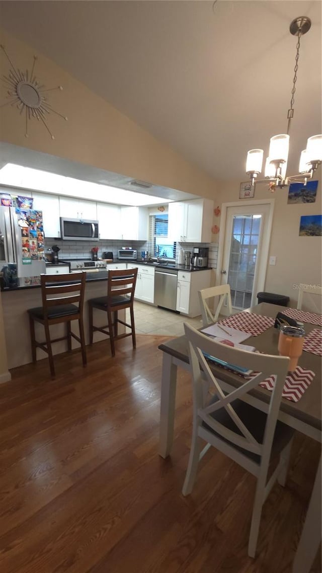 dining room featuring an inviting chandelier, hardwood / wood-style floors, and vaulted ceiling