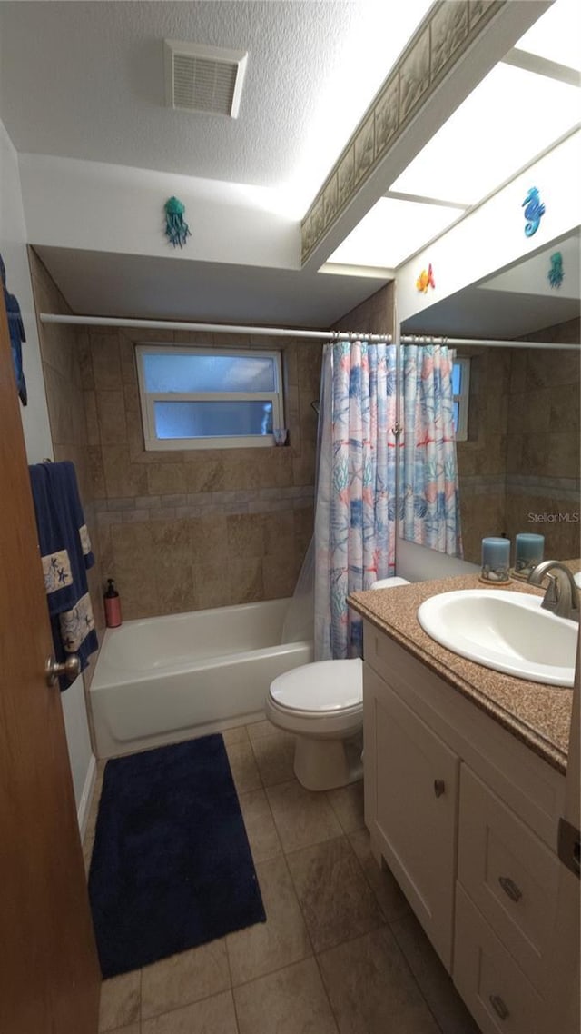 full bathroom with toilet, a textured ceiling, vanity, shower / bath combo with shower curtain, and tile patterned flooring