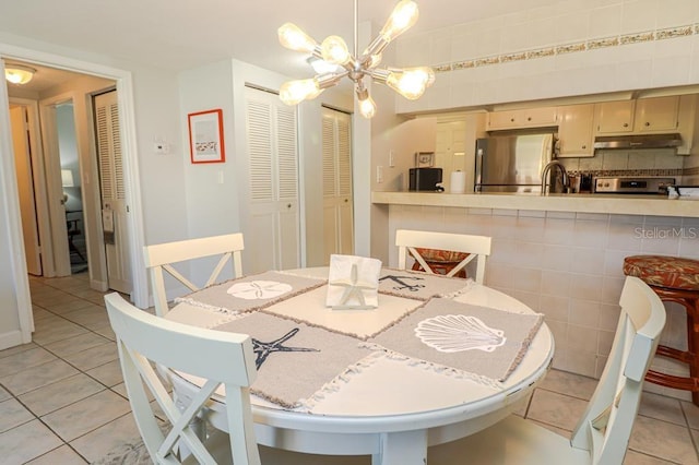 tiled dining space featuring a chandelier and sink