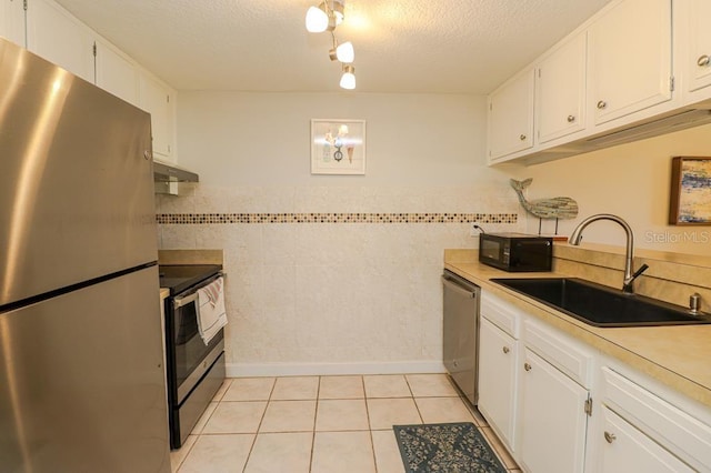 kitchen featuring light tile patterned floors, stainless steel appliances, white cabinets, and sink