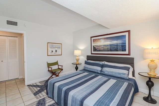 bedroom featuring a textured ceiling, a closet, and light tile patterned floors