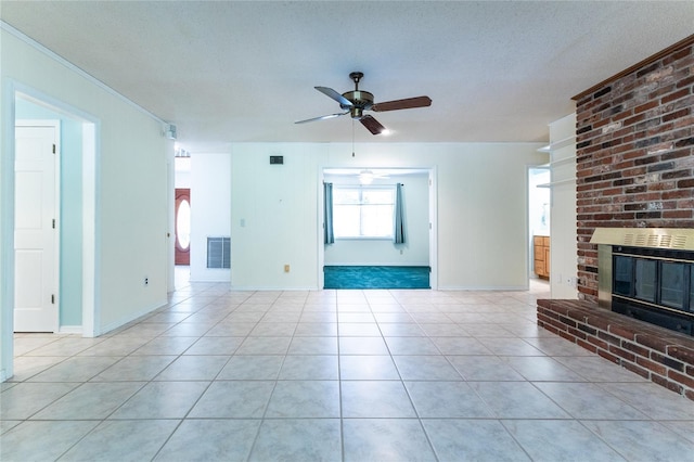 unfurnished living room featuring ceiling fan, light tile patterned floors, a fireplace, and a textured ceiling