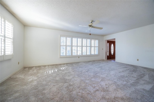 spare room with plenty of natural light, a textured ceiling, carpet, and ceiling fan