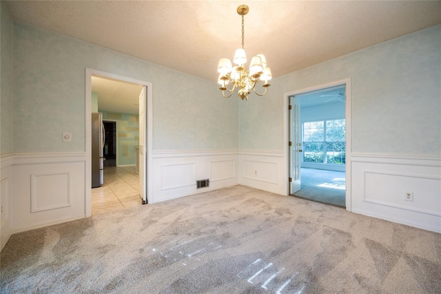 carpeted empty room with a notable chandelier