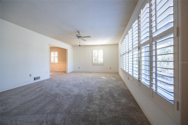 empty room featuring a textured ceiling, ceiling fan, and carpet flooring