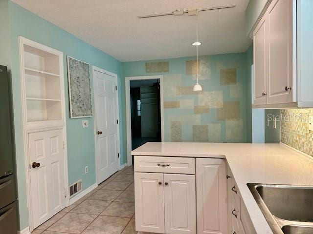 kitchen with white cabinetry, decorative backsplash, hanging light fixtures, light tile patterned floors, and kitchen peninsula