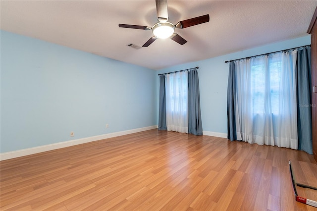 spare room featuring a textured ceiling, plenty of natural light, light hardwood / wood-style floors, and ceiling fan