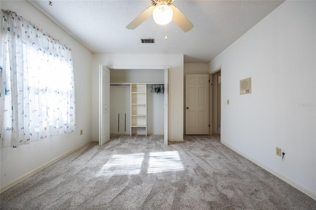 unfurnished bedroom featuring light colored carpet, a textured ceiling, ceiling fan, and a closet