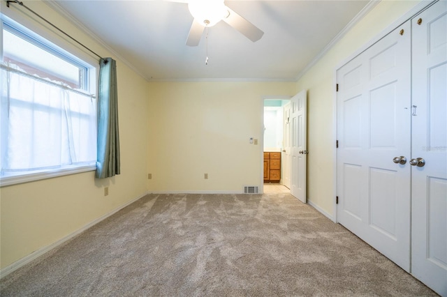 unfurnished bedroom featuring light carpet, ornamental molding, a closet, and ceiling fan