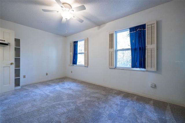 empty room with ceiling fan, carpet, and a textured ceiling