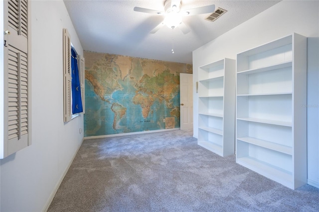 unfurnished room with a textured ceiling, built in features, ceiling fan, and carpet flooring