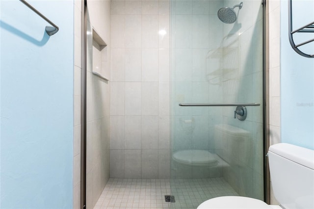 bathroom featuring a shower with door and toilet