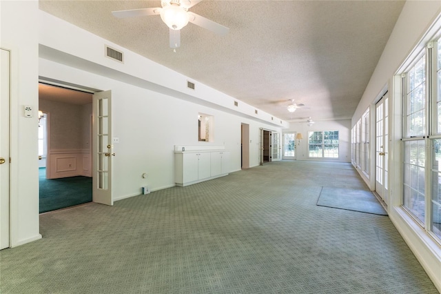 spare room featuring ceiling fan, carpet floors, a textured ceiling, and french doors