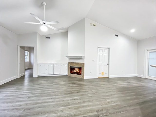 unfurnished living room with ceiling fan, light wood-type flooring, high vaulted ceiling, and a fireplace