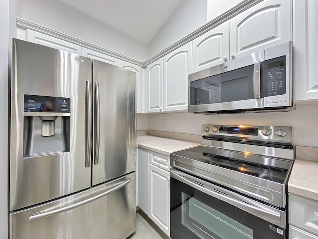 kitchen with white cabinetry, lofted ceiling, and stainless steel appliances