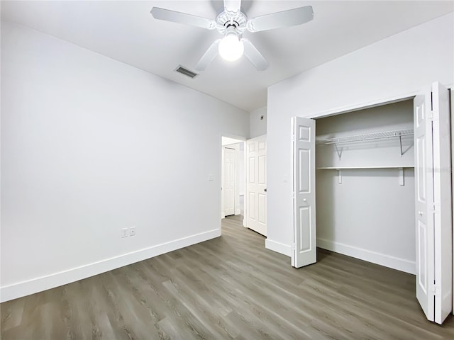 unfurnished bedroom featuring ceiling fan, dark hardwood / wood-style flooring, and a closet