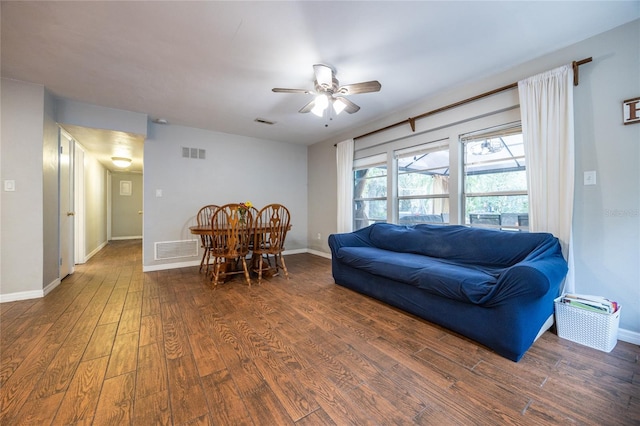 living room with ceiling fan and dark wood-type flooring