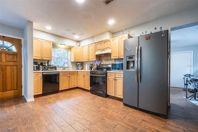 kitchen with hardwood / wood-style floors, decorative backsplash, light brown cabinets, black appliances, and sink