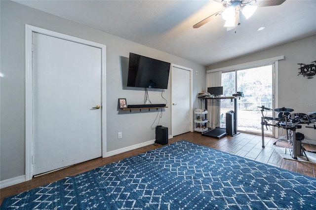 exercise room with ceiling fan, dark hardwood / wood-style floors, and vaulted ceiling