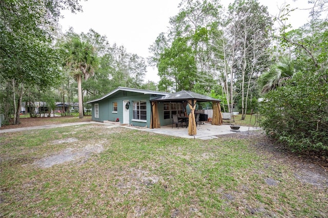 back of property with a gazebo, a patio, and a yard