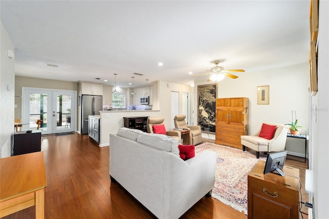 living room with ceiling fan, french doors, and dark hardwood / wood-style flooring