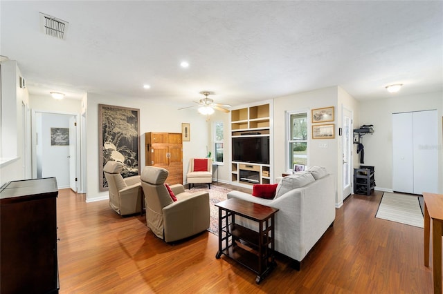 living room with ceiling fan, hardwood / wood-style flooring, and built in shelves