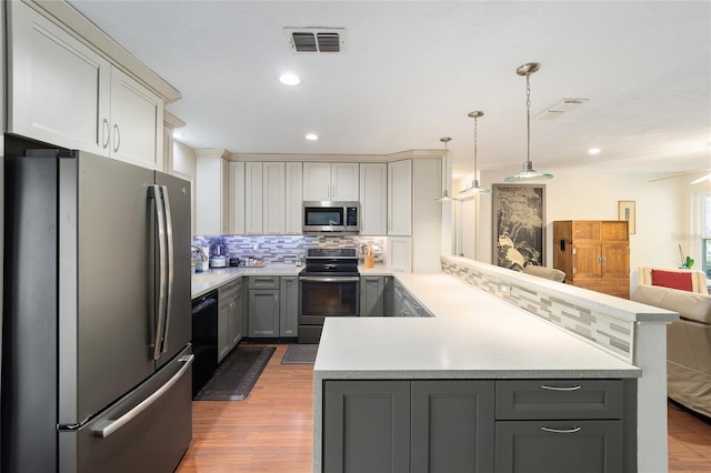 kitchen featuring kitchen peninsula, gray cabinets, appliances with stainless steel finishes, backsplash, and hanging light fixtures