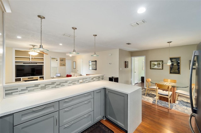 kitchen with ceiling fan, gray cabinetry, backsplash, dark wood-type flooring, and hanging light fixtures