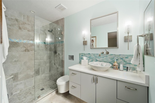 bathroom with toilet, tiled shower, backsplash, and vanity