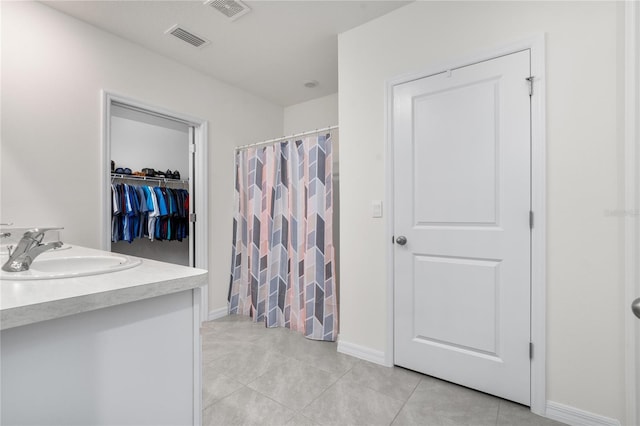 bathroom featuring tile patterned flooring, walk in shower, and vanity