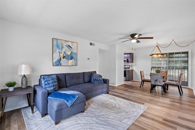 living room featuring hardwood / wood-style flooring, a textured ceiling, and ceiling fan