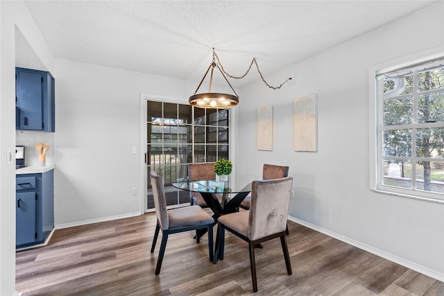 dining space with a textured ceiling, dark hardwood / wood-style floors, and a notable chandelier