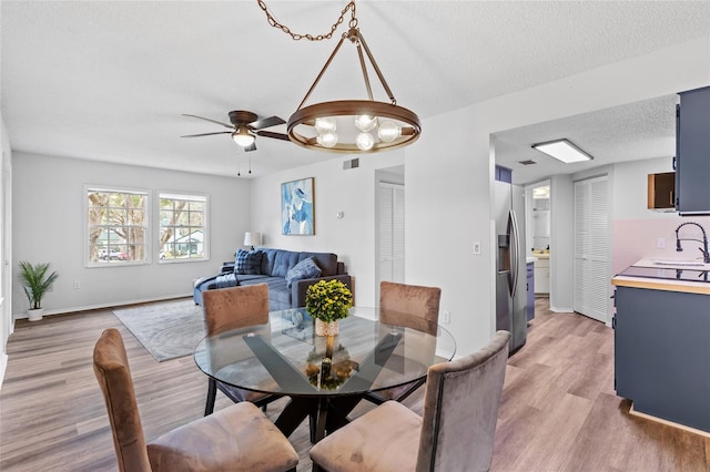 dining space featuring sink, a textured ceiling, and light wood-type flooring